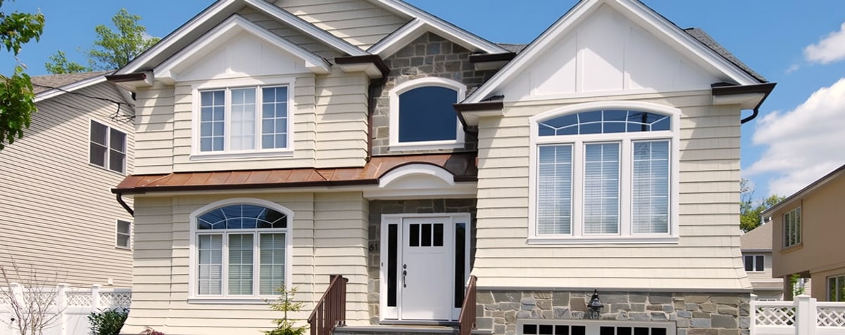 Beige siding house with stone base and arched windows
